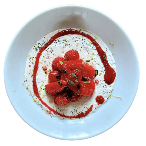 Dessert élégamment dressé aux framboises fraîches, crème blanche, coulis rouge et éclats de pistache au Le Grand Duc
