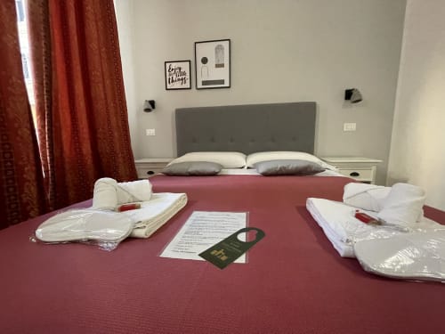 Double bed with burgundy spread and white pillows at AD Trastevere Guest House in Rome, Italy