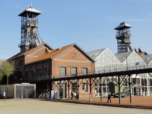 Historic mining site architecture in Valenciennes with twin pit head towers and brick buildings