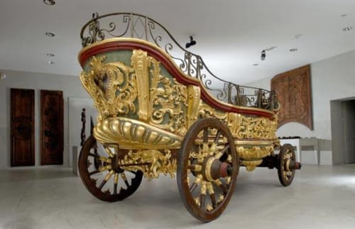 Ornate golden ceremonial carriage with red canopy at Le Grand Duc boutique hotel in Valenciennes, France