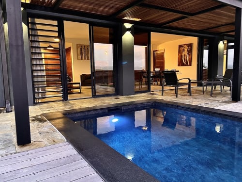 Villa Passion Cannelle aux Trois-Ilets avec piscine privée illuminée, terrasse en bois et portes vitrées donnant sur