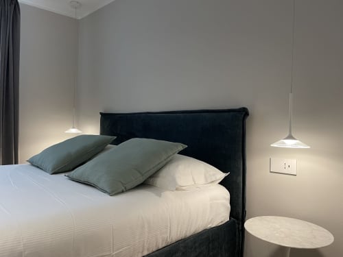 Camera moderna al Covo del Pirata Venice con letto imbottito nero, biancheria bianca, cuscini salvia e illuminazione a sospensione
