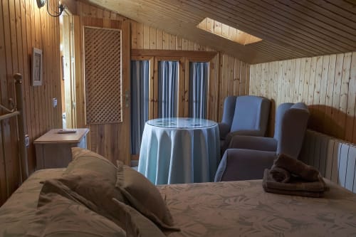 Acogedor dormitorio en Casa Rural Las Cuevas De Setenil con revestimiento de madera, cama, zona de estar y cortinas azules a rayas