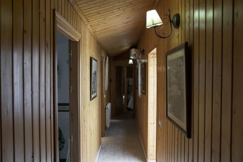 Pasillo de madera en Casa Rural Las Cuevas De Setenil con puertas, apliques de pared y cuadros enmarcados