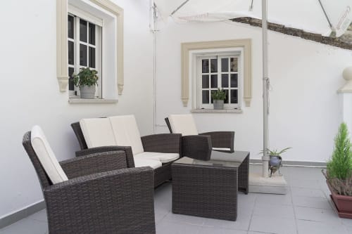 Área de estar al aire libre en la terraza de Casa Rural Las Cuevas De Setenil con muebles de mimbre y cojines blancos