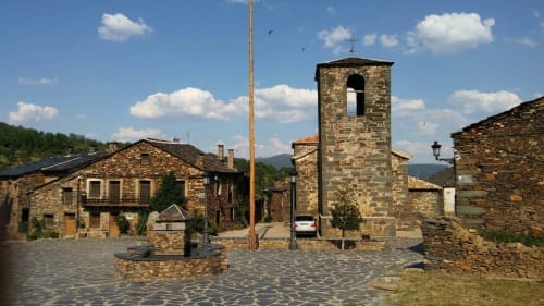 Patio de piedra de Casa Rural La Perla con la torre de la iglesia en Hiendelaencina, España