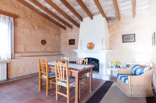 Sa Casa Rotja | Sineu, España -Este apartamento es el más grande, ideal para grupos de amigos, una gran família o dos famílias. Tiene una gran sala comedor con chimenea en la planta de abajo. Con una gran mesa para 8 personas o más. Además dispone de sofás y butacas para descansar.  En la planta superior está la cocina con todo lo necesario para cocinar y comer, la terraza privada con vistas al patio, el baño completo y las tres habitaciones.
En cada habitación hay dos camas individuales.