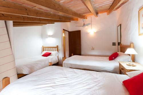 Sa Casa Rotja | Sineu, España -Este apartamento es el más grande, ideal para grupos de amigos, una gran família o dos famílias. Tiene una gran sala comedor con chimenea en la planta de abajo. Con una gran mesa para 8 personas o más. Además dispone de sofás y butacas para descansar. En la planta superior está la cocina con todo lo necesario para cocinar y comer, la terraza privada con vistas al patio, el baño completo y las tres habitaciones. En cada habitación hay dos camas individuales.