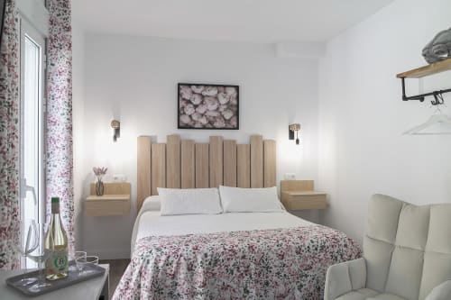 Acogedora habitación en Casa Rural Las Cuevas De Setenil con cabecero de madera, ropa de cama floral y mesitas de noche gemelas