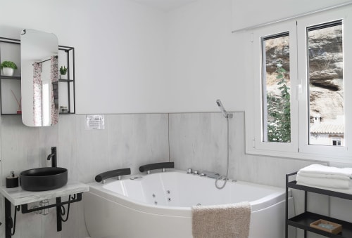Baño moderno con lavamano redondo negro, bañera de inmersión blanca y vistas al río en Casa Rural Las Cuevas De Setenil, Cádiz