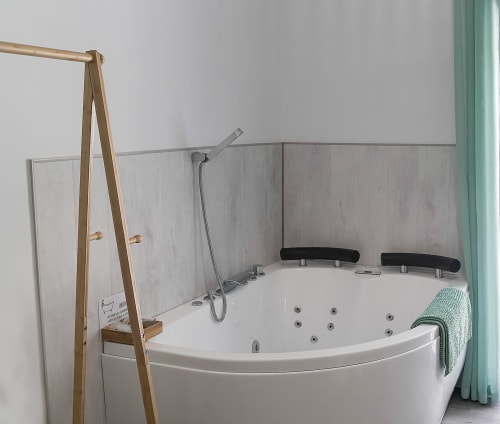 Lujosa bañera de esquina con hidromasaje y ducha de mano en Casa Rural Las Cuevas De Setenil