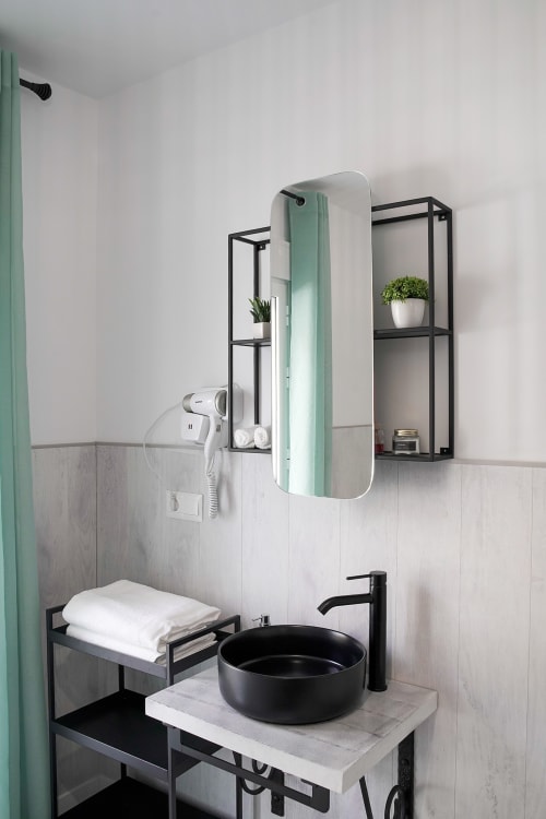 Baño moderno en Casa Rural Las Cuevas de Setenil con lavabo negro, detalles en menta y accesorios elegantes