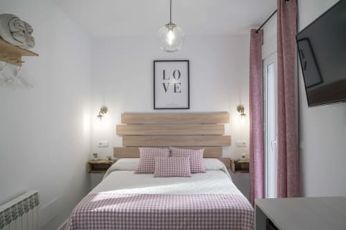 Dormitorio moderno en Casa Rural Las Cuevas De Setenil con cabecero de madera, ropa de cama a cuadros rosa, luz colgante y Love