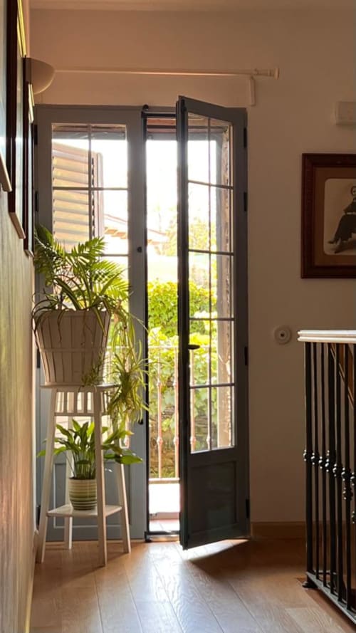 Portes vitrées avec cadre noir ouvrant sur la vue du jardin de la maison rurale Casa Rural La Perla à Hiendelaencina, avec plantes en pots et