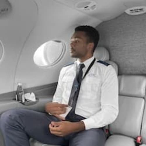 Businessman in white shirt seated in private airplane cabin near window