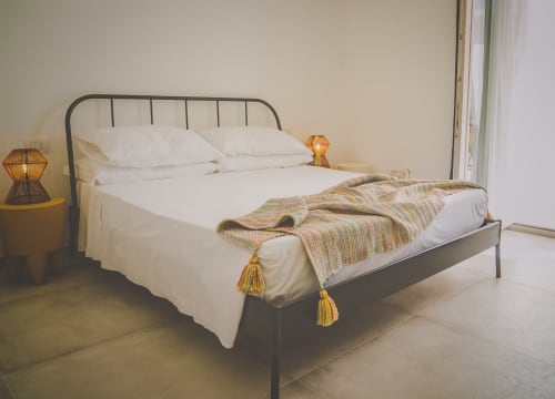 Camera moderna a Casa Ziazì a Monopoli con letto in ferro battuto, biancheria bianca e coperta a righe