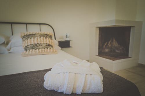 Camera da letto lusso a Casa Ziazì con asciugamani arrotolati, camino, letto in metallo e biancheria color crema a Monopoli
