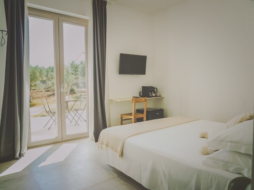 Camera Superior luminosa a Casa Ziazì a Monopoli con letto bianco, TV a schermo piatto e terrazza con vista sul giardino e posti a sedere