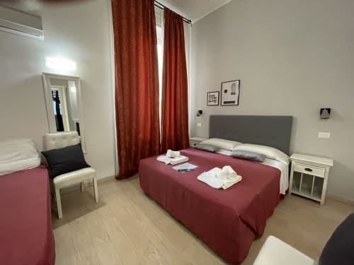 Double bedroom with burgundy bedding at AD Trastevere Guest House in Rome, featuring gray headboard and red curtains