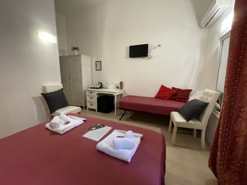 Spacious room at AD Trastevere Guest House in Roma with burgundy beds, seating area, desk, and wall-mounted TV