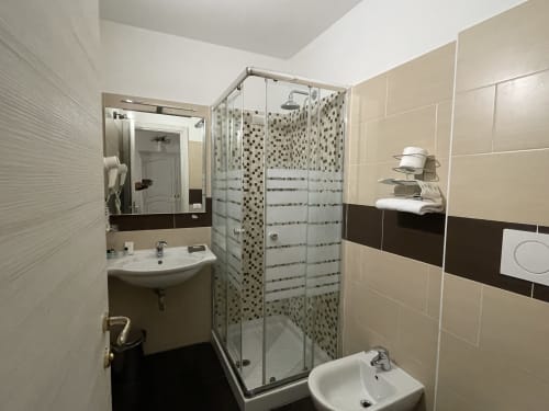 Modern bathroom at AD Trastevere Guest House Rome with glass shower enclosure, beige tiles, and dual sinks