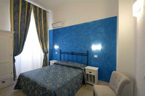 Camera moderna dell'AD Trastevere Guest House a Roma con parete accent blu, biancheria patterned e arredi eleganti