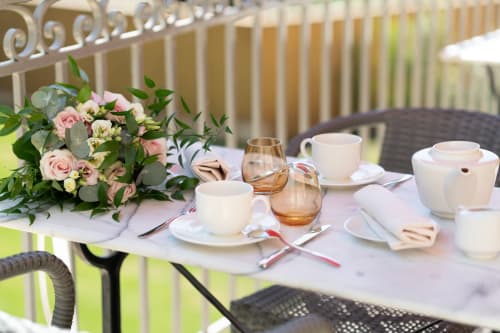 Elegant outdoor tea service at Pavillon Des Millesimes SPA with floral arrangements and white tableware