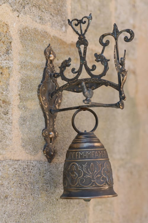 Cloche de bronze ornementale vintage à décor de volutes accrochée au mur du Pavillon Des Millésimes & SPA, Lussac, France