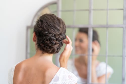 Femme aux cheveux attachés en tresse devant le miroir d'un spa hôtel de luxe à Lussac, France
