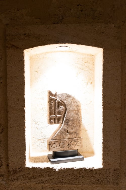Sculpture de tête de cheval en pierre ancienne exposée dans une niche voûtée au Pavillon des Millésimes, Lussac