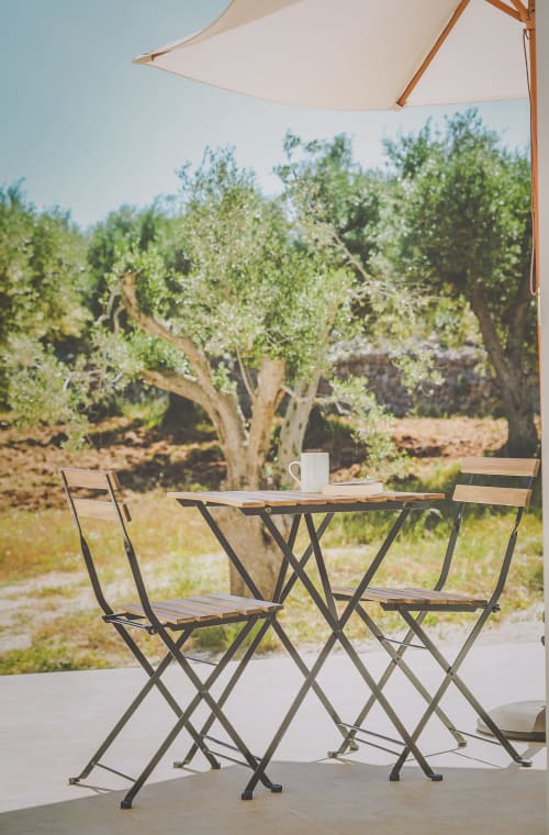 Area di seduta esterna di Casa Ziazì con vista sul giardino, ombrellone e ulivi a Monopoli, Italia