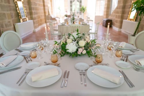 Élégante mise en place de banquet nuptial au Pavillon Des Millésimes avec couverts blancs, composition florale et accents dorés