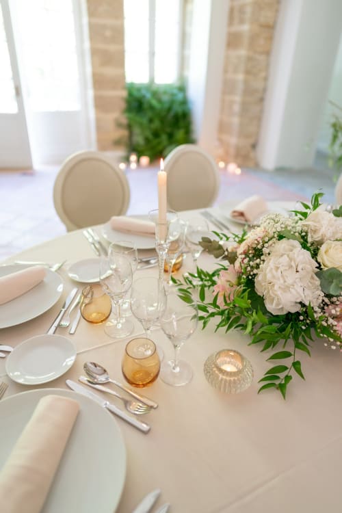 Elegant table setting at Pavillon Des Millesimes with white plates, cream flowers, and candlelight in Lussac