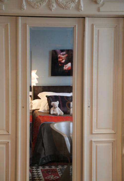 Bedroom doorway at Le Grand Duc BnB in Valenciennes with bed, white teddy bear, and artwork