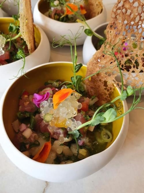 Elegant plated dish with ceviche, caviar pearls, edible flowers at Pavillon Des Millesimes in Lussac