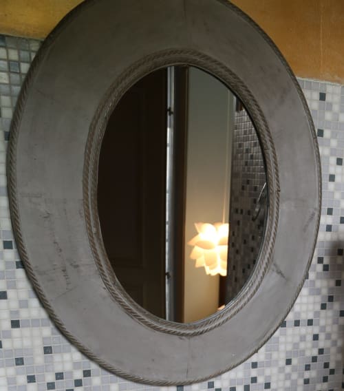 Oval bathroom mirror with rope frame at Le Grand Duc boutique hotel in Valenciennes, reflecting warm bathroom lighting and