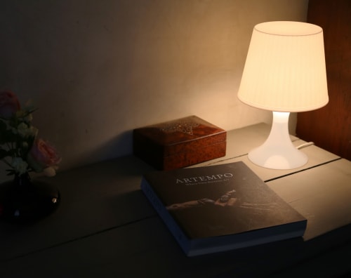 Elegant bedside lamp illuminating books and wooden box in Chapter 2 room at Le Grand Duc, Valenciennes