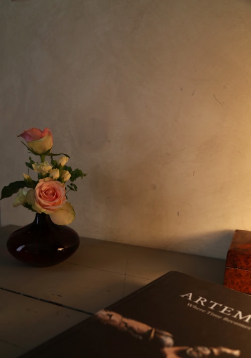 Elegant floral arrangement in black vase with roses beside book on desk at Le Grand Duc boutique hotel in Valenciennes