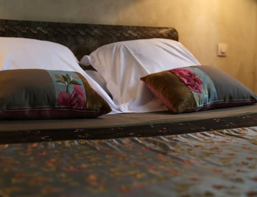 Elegantly styled bed at Le Grand Duc in Valenciennes with decorative floral pillows and white linens in Chapter 2 room