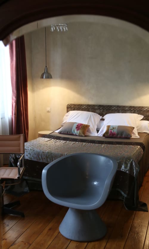 Modern bedroom at Le Grand Duc B&B in Valenciennes with pendant lighting, blue chair, and white bedding