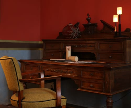 Elegant office workspace at Le Grand Duc with rich wood desk, mustard chair, and red accent wall in Valenciennes