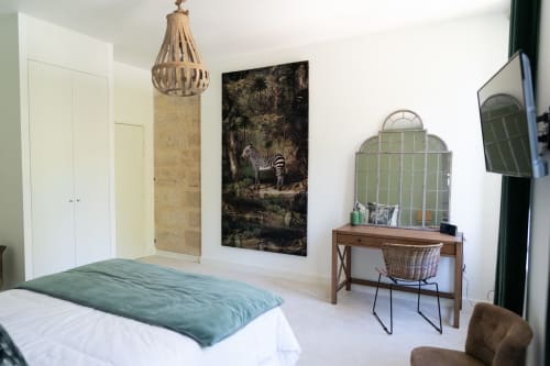 An elegant room at the Pavillon Des Millésimes featuring a wooden headboard, a palette of greens, a green armchair, and views of the pool and landscaped garden