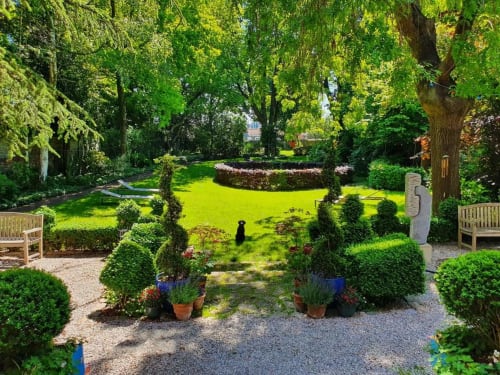 Jardin verdoyant du Le Grand Duc B&B à Valenciennes avec haies taillées, pelouse et pots en terre cuite