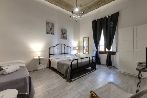 Camera spaziosa presso Sleep tight Florence con letto in metallo nero, letto singolo gemello, soffitto ornato, tende scure e giardino