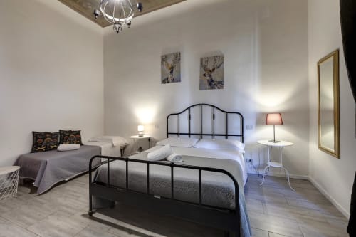 Bright Florence apartment bedroom with two metal beds, white linens, wall art, and garden views at Sleep Tight Florence