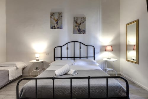 Modern Florence apartment bedroom with black metal bed frame, white linens, twin nightstands, and decorative deer artwork