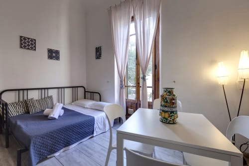 Bright Florence apartment bedroom with garden view, featuring metal bed frame, white desk, balcony access, and modern