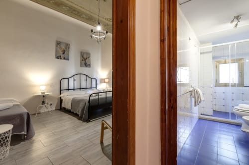Spacious apartment bedroom with ensuite bathroom at Sleep tight Florence B&B, featuring metal bed frame and garden views