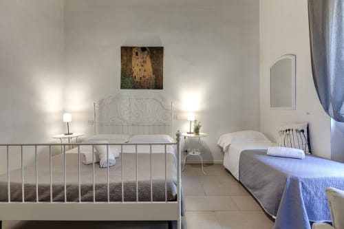 Bright modern bedroom at Sleep tight Florence with two beds, white metal frames, bedside lamps, and Gustav Klimt artwork on