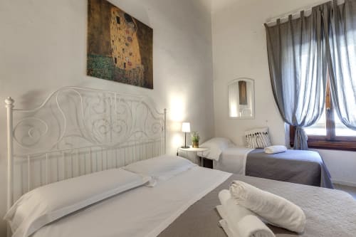 Bright bedroom in Sleep tight Florence apartment with white ornate bed, twin beds, large windows, and Klimt artwork in